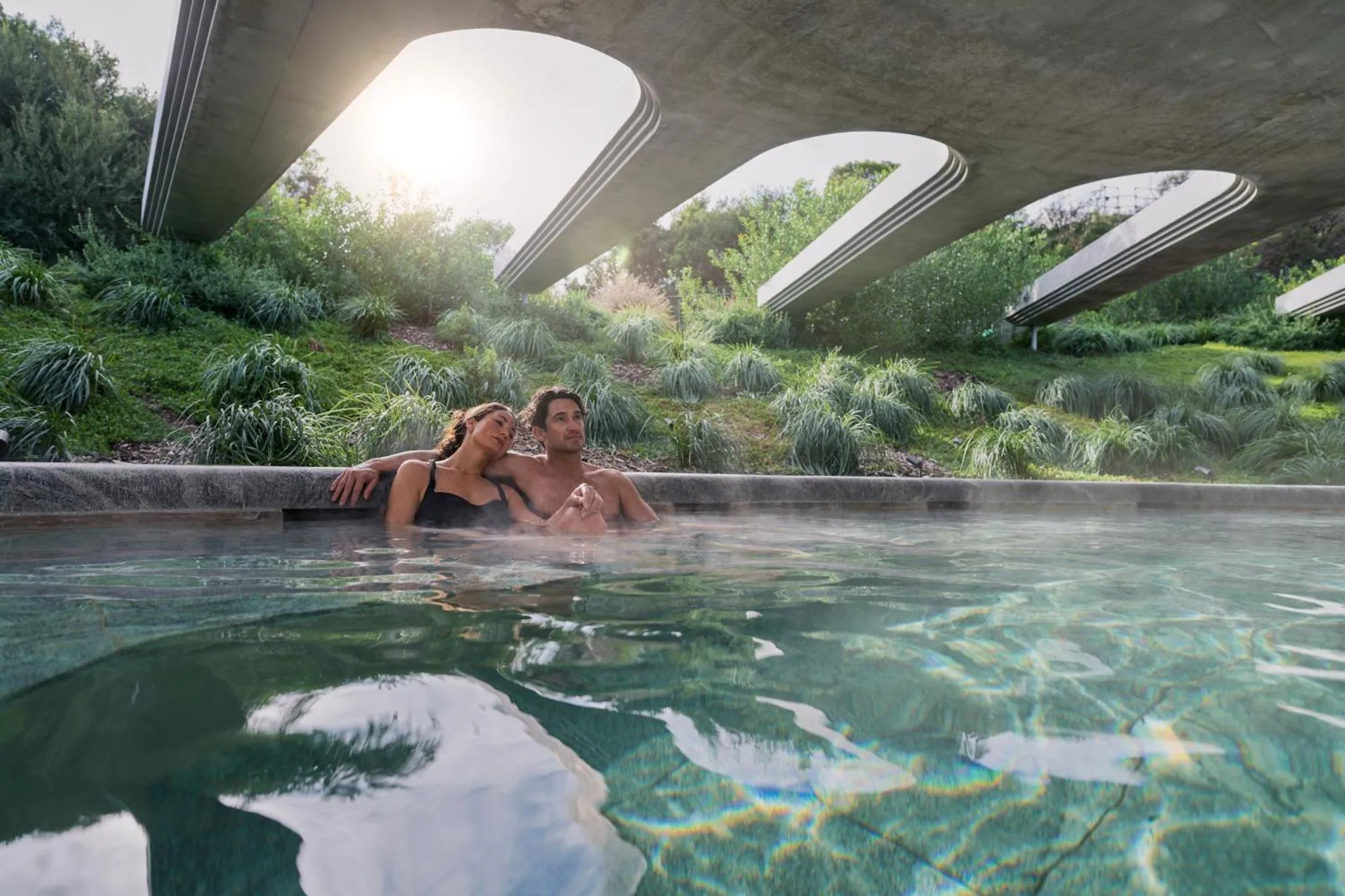 Un couple se détend dans une piscine extérieure ensoleillée.
