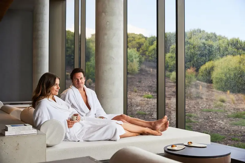 Un couple se détend sur un canapé face à une grande baie vitrée.