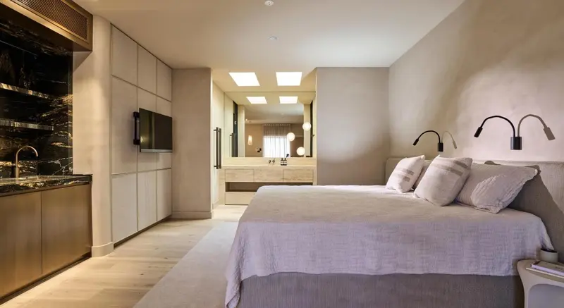 Une chambre lumineuse avec un grand lit et un espace lavabo.