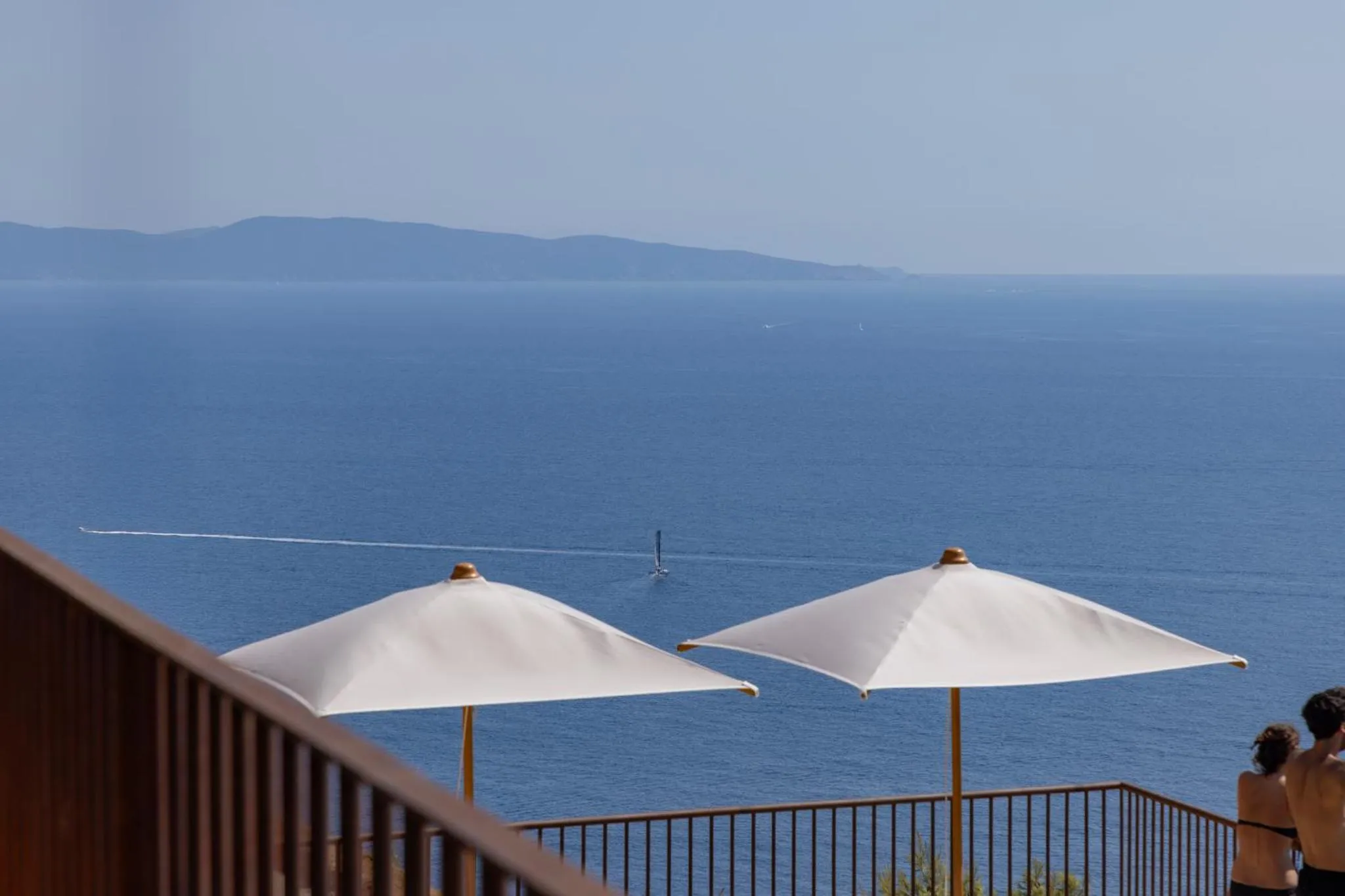 Vue sur la mer depuis une terrasse ombragée.