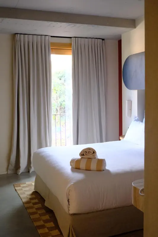 Une chambre lumineuse avec un lit recouvert d'une courtepointe blanche et de coussins.