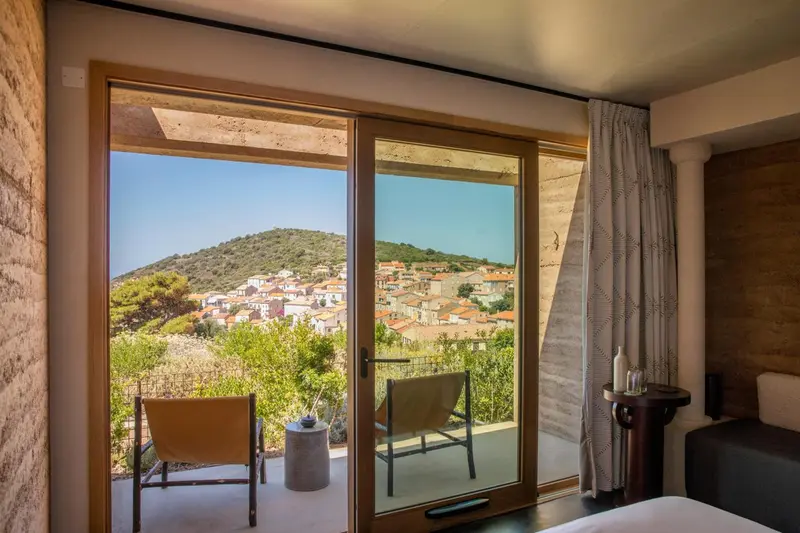 Une chambre avec vue sur un village et une colline verdoyante.