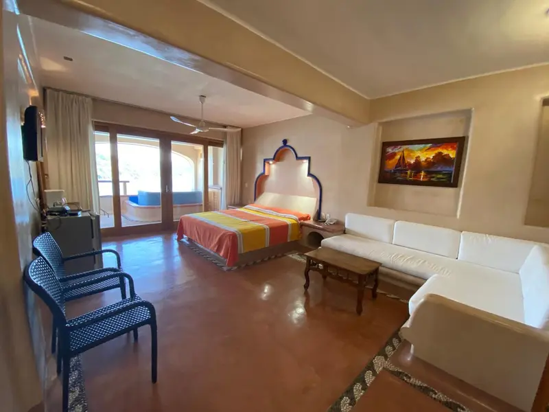 Une chambre lumineuse avec un grand lit et un coin salon.