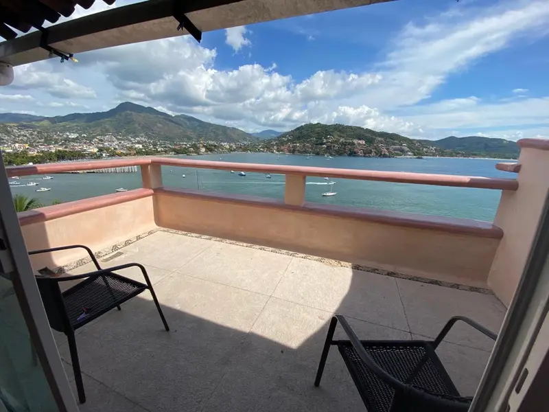 Terrasse avec mobilier d'extérieur donnant sur une baie et des montagnes.