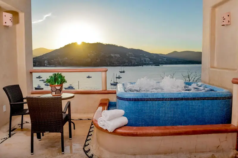 Terrasse avec jacuzzi et vue sur la mer au coucher du soleil.