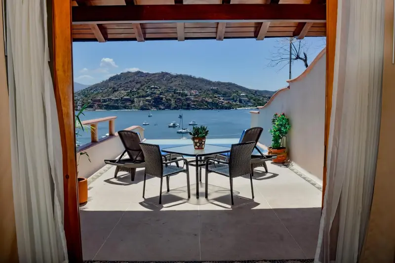 Terrasse avec mobilier de jardin donnant sur une baie ensoleillée.