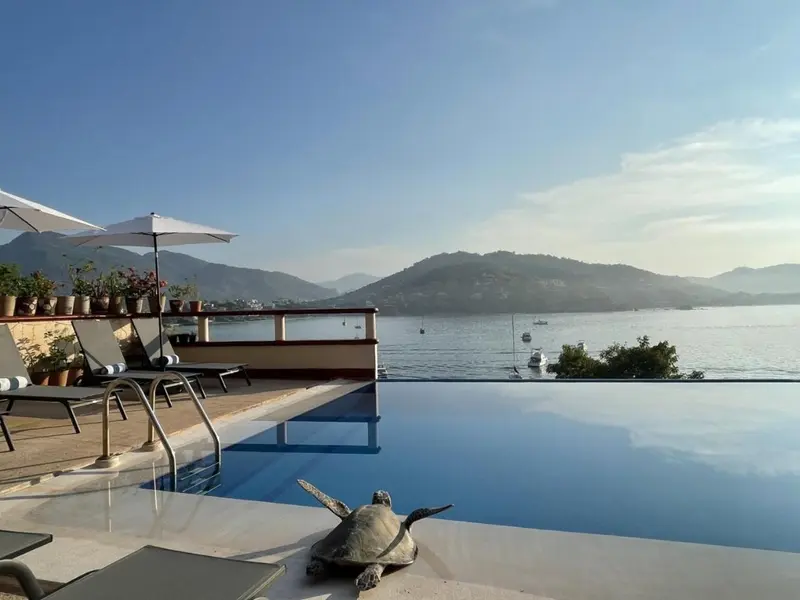 Terrasse avec transats et piscine à débordement donnant sur la mer.