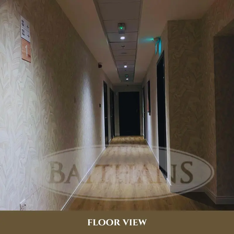 Un long couloir d'hôtel avec des portes de chambres de chaque côté.