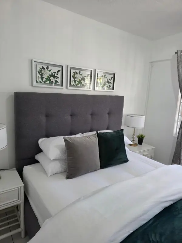 Une chambre lumineuse avec un grand lit recouvert de coussins.