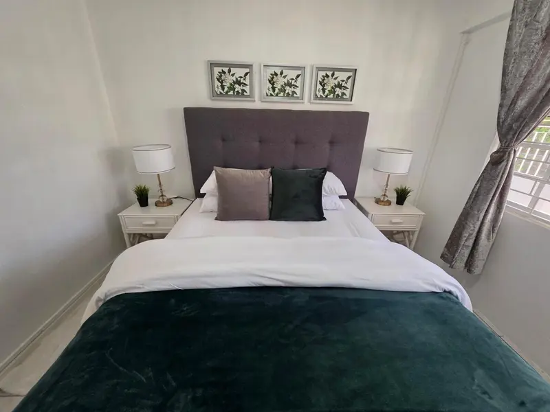 Une chambre avec un grand lit recouvert d'une couette verte et de coussins.