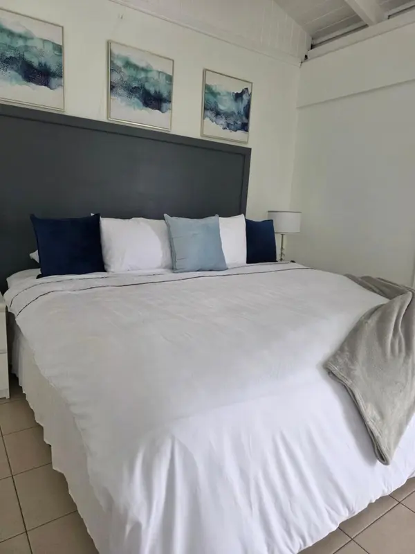 Une chambre lumineuse avec un grand lit recouvert de linge blanc et de coussins bleus.