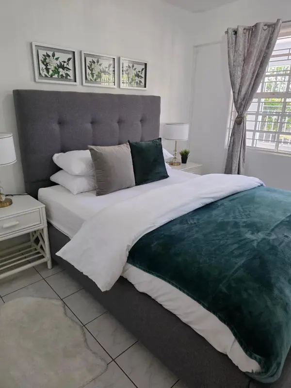 Une chambre lumineuse avec un grand lit recouvert d'une couverture verte.