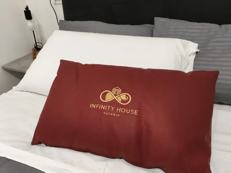 Un lit avec des oreillers blancs et un coussin décoratif.