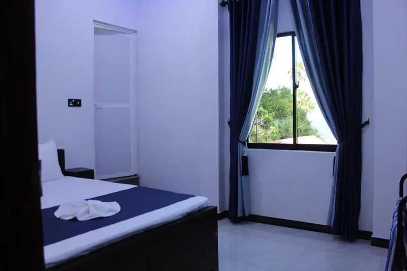 Une chambre lumineuse avec un lit recouvert d'une couverture blanche et bleue.