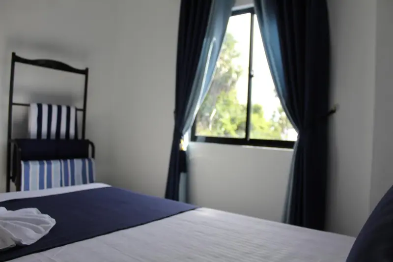 Une chambre lumineuse avec un lit recouvert d'une couverture bleue et rayée.
