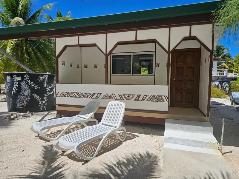 Deux transats blancs invitent à la détente devant un bungalow clair.