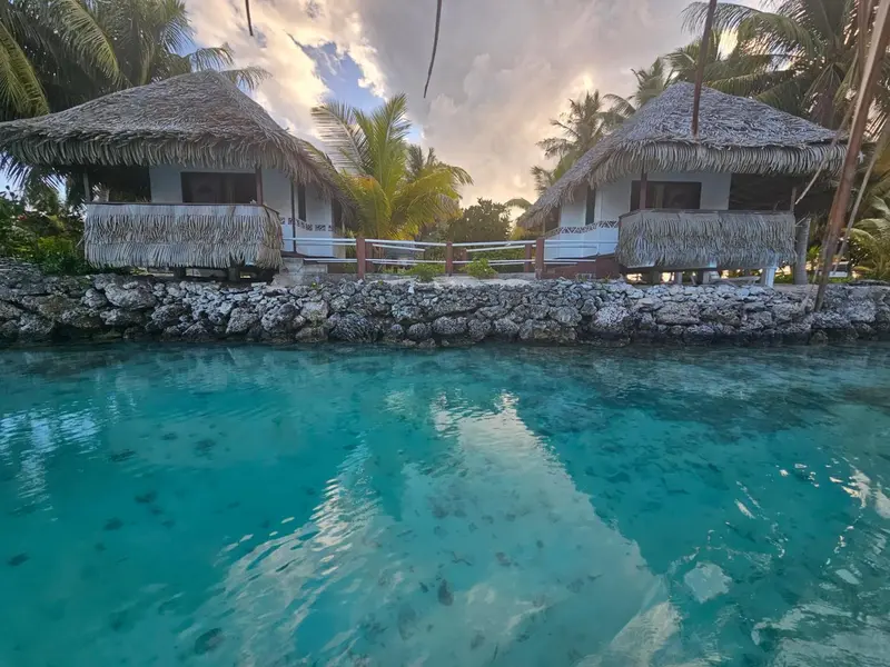 Des bungalows sur pilotis surplombent une eau turquoise et peu profonde.