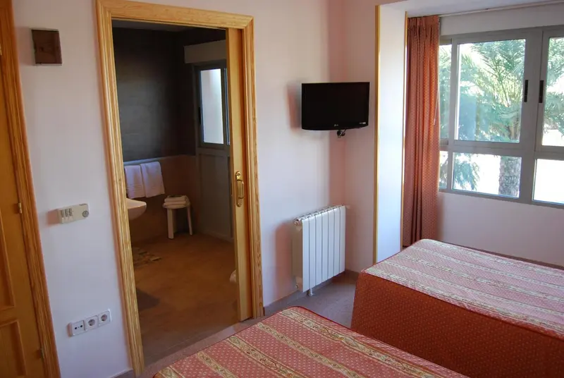 Une chambre lumineuse avec deux lits et un accès à une salle de bain.