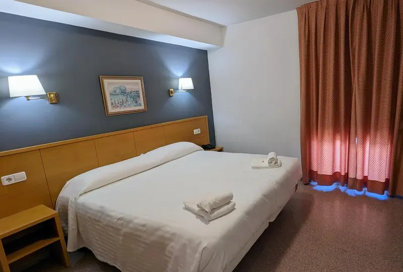 Une chambre d'hôtel lumineuse avec un lit simple et des lampes de chevet.