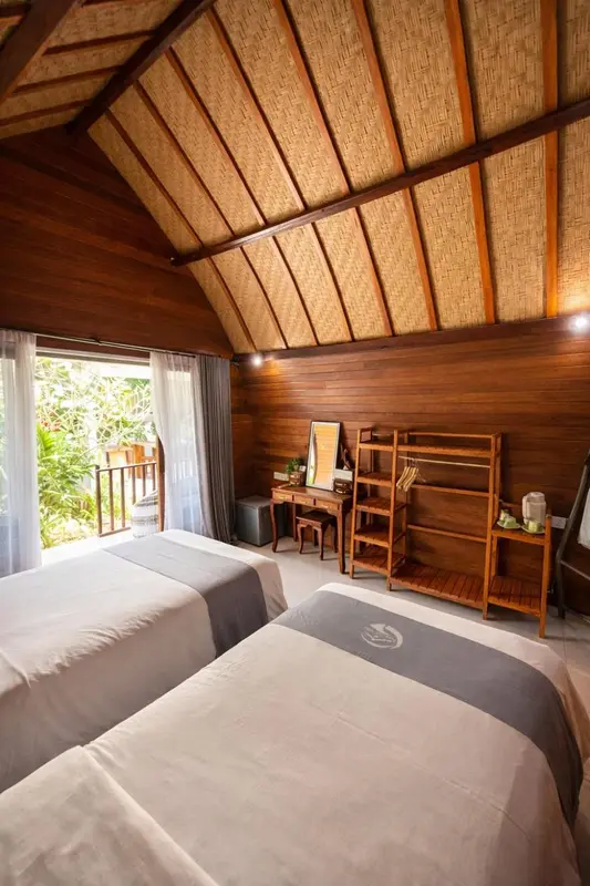 Chambre lumineuse avec deux lits et mobilier en bois.