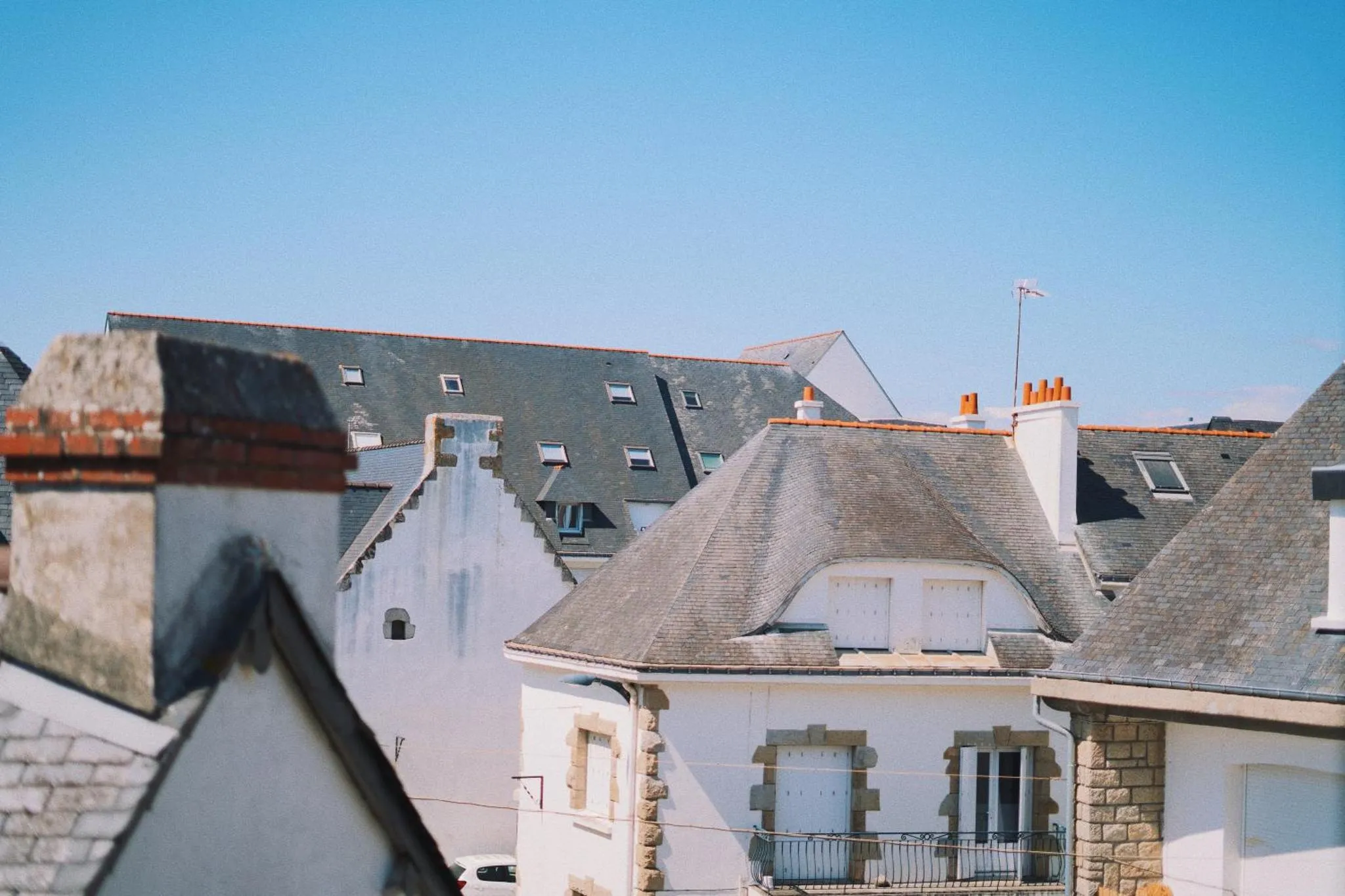Toits d'habitations aux couleurs claires sous un ciel bleu.