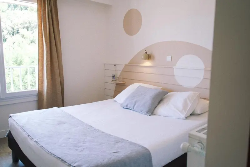 Une chambre lumineuse avec un grand lit et une décoration murale.