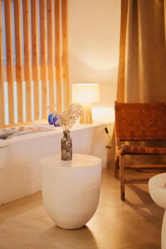Une table ronde blanche avec un vase orne une piece lumineuse.