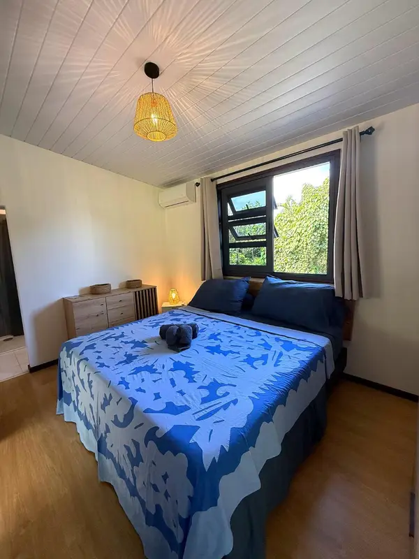 Une chambre lumineuse avec un grand lit recouvert d'une courtepointe à motifs.