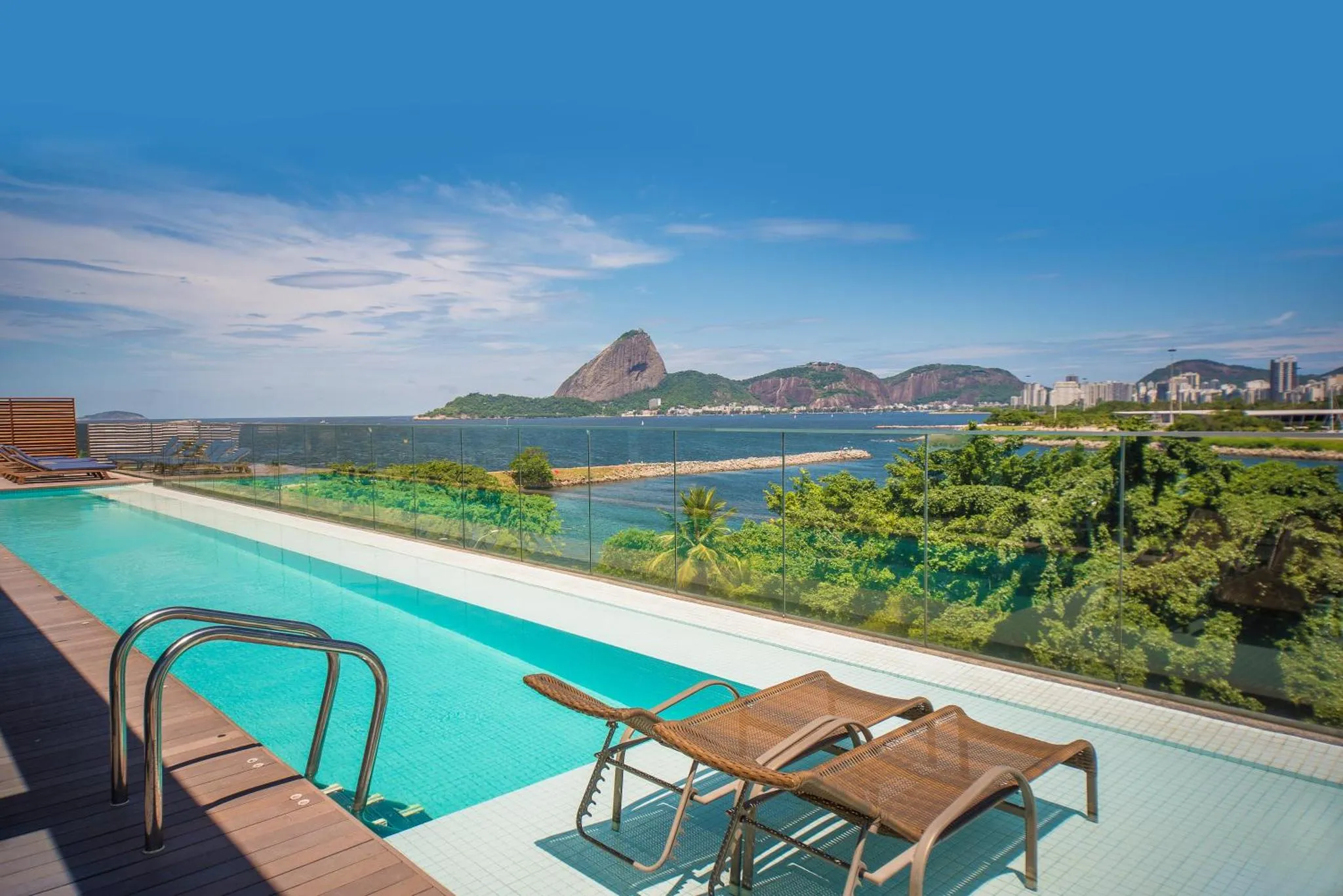 Deux transats se trouvent au bord d'une piscine avec vue sur la mer et les montagnes.