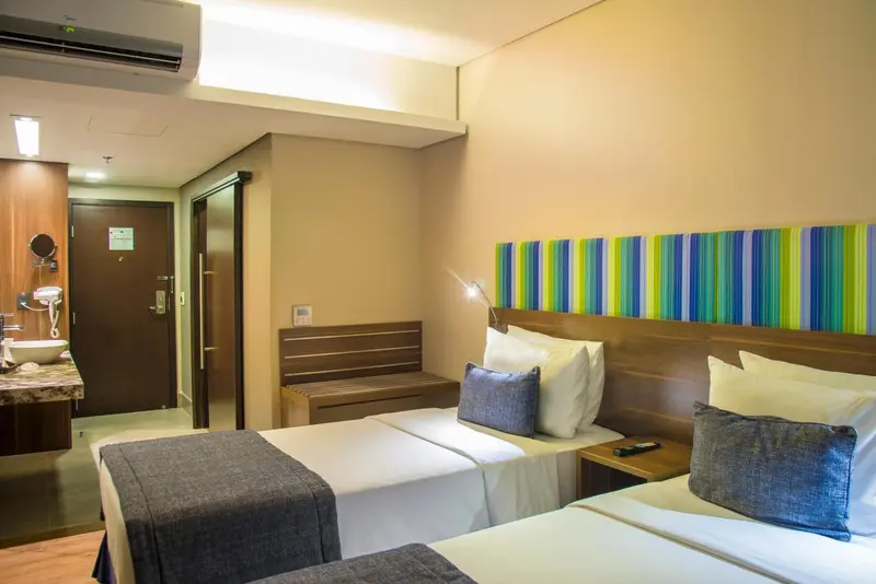 Une chambre d'hôtel avec deux lits simples et une décoration murale colorée.