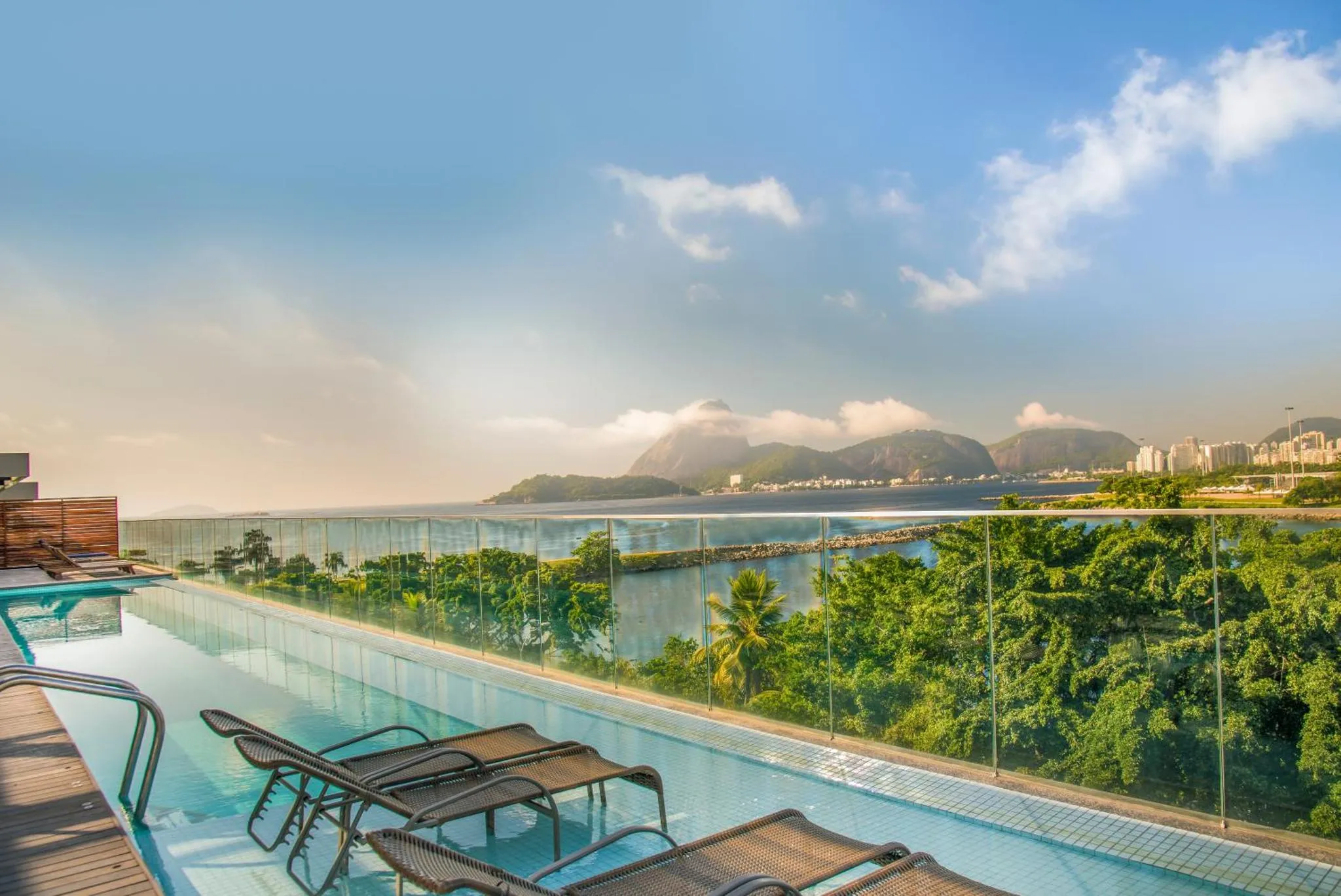 Transats alignés au bord d'une piscine à débordement avec vue sur la mer et les montagnes.