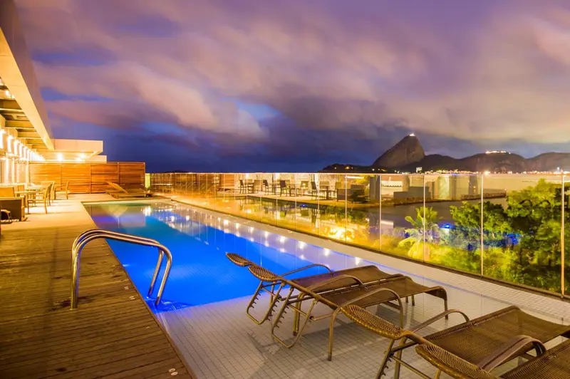 Terrasse avec piscine illuminée donnant sur une vue nocturne de la ville.