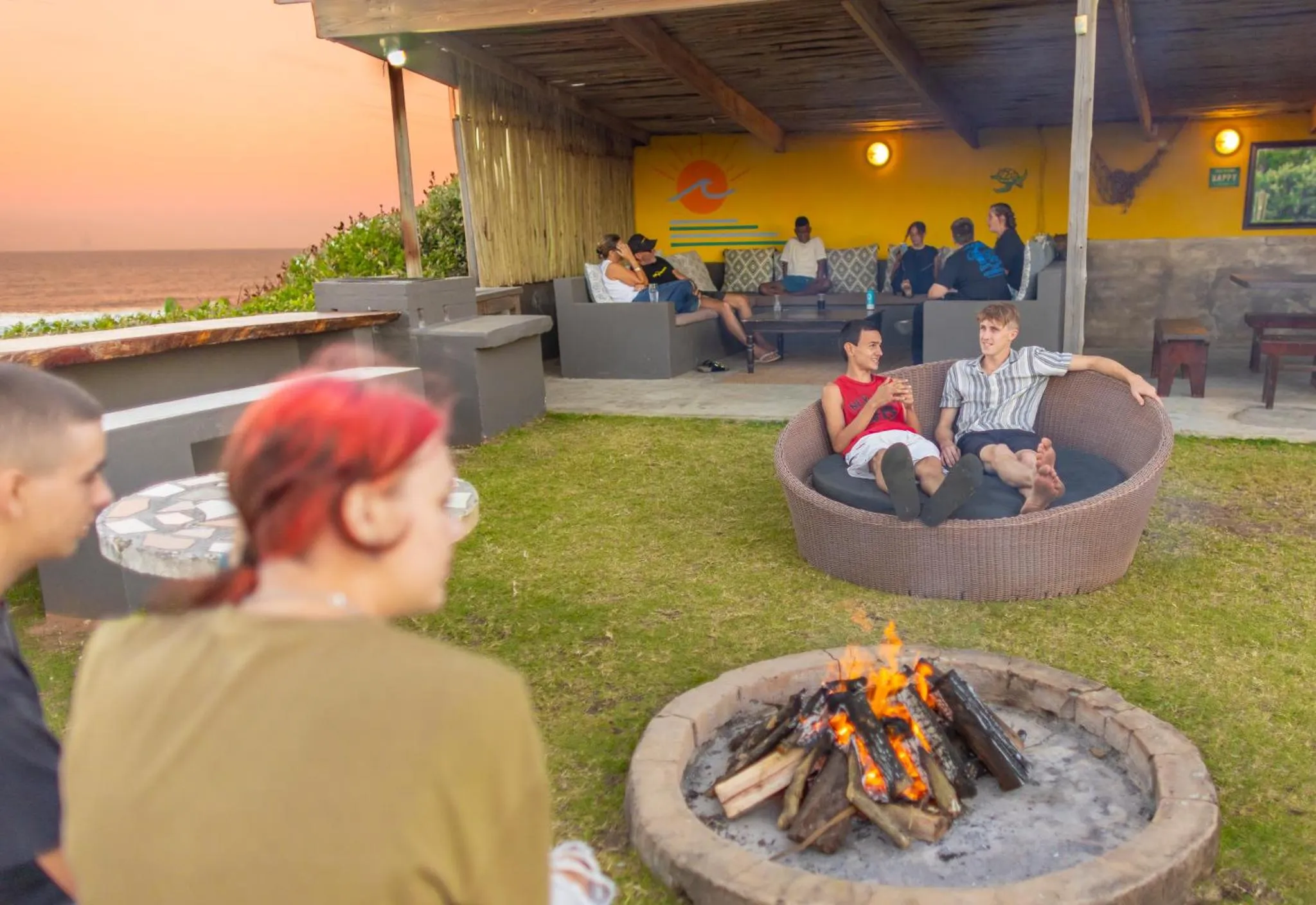 Des personnes se détendent sur une terrasse avec un foyer extérieur.