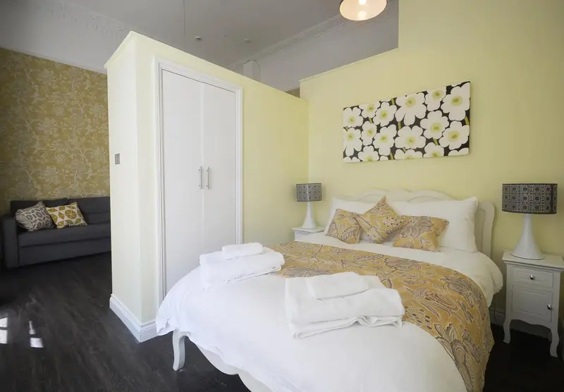 Une chambre lumineuse avec un lit fait et un canapé d'angle.