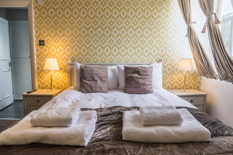 Une chambre lumineuse avec un grand lit recouvert d'une couverture et de coussins.