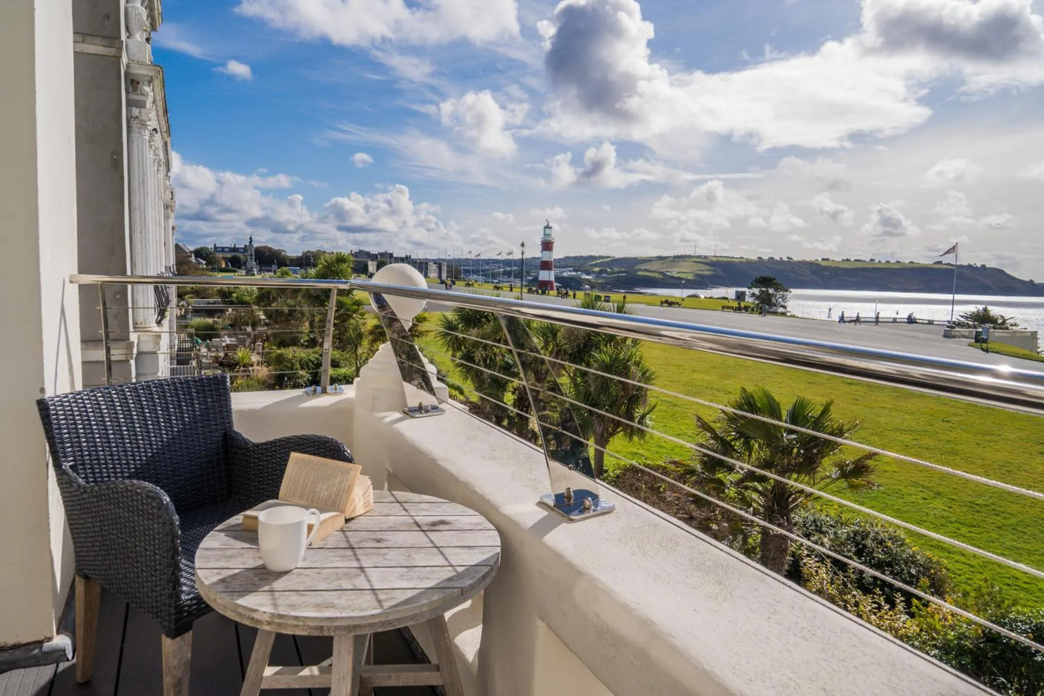 Une terrasse avec une table basse et des fauteuils offre une vue sur la mer et la côte.