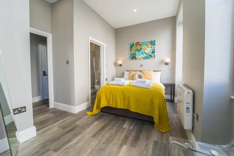 Une chambre lumineuse avec un grand lit recouvert d'une couverture jaune.