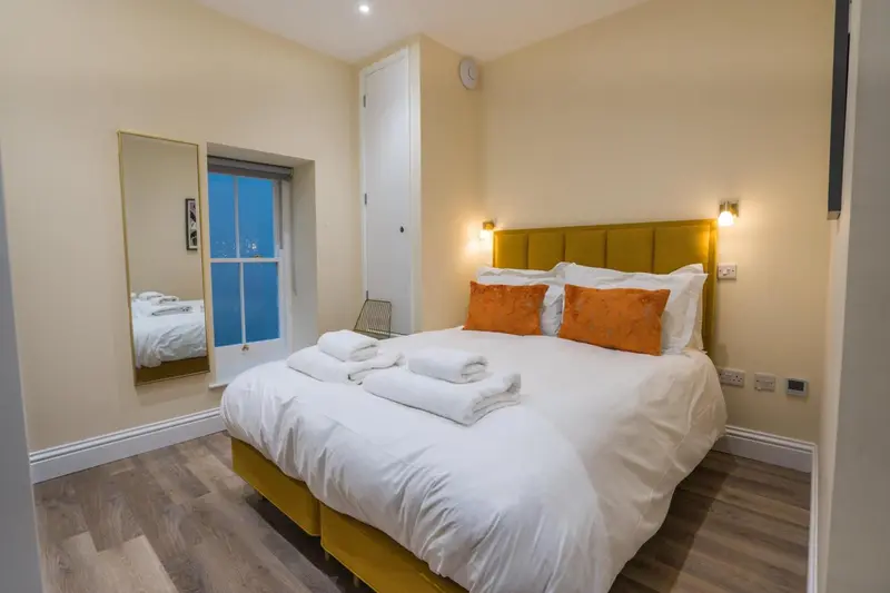 Une chambre lumineuse avec un grand lit recouvert de coussins et de couvertures.