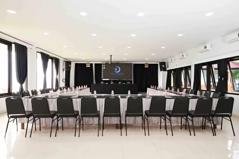 Une salle de réunion lumineuse avec des tables et des chaises disposées en U.