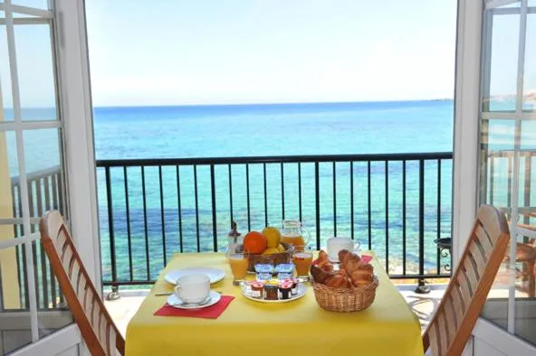 Une table de petit-déjeuner est dressée sur une terrasse avec vue sur la mer.
