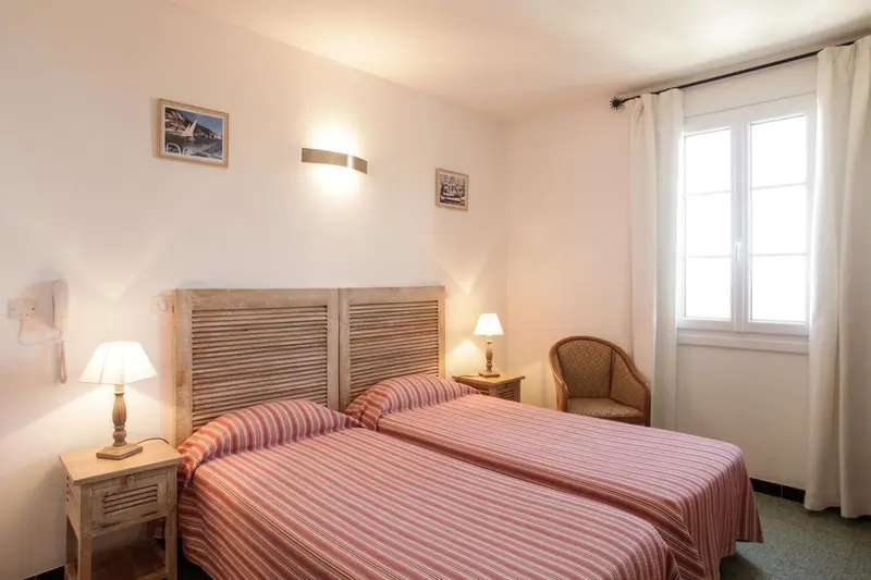 Une chambre avec deux lits simples et une fenêtre.