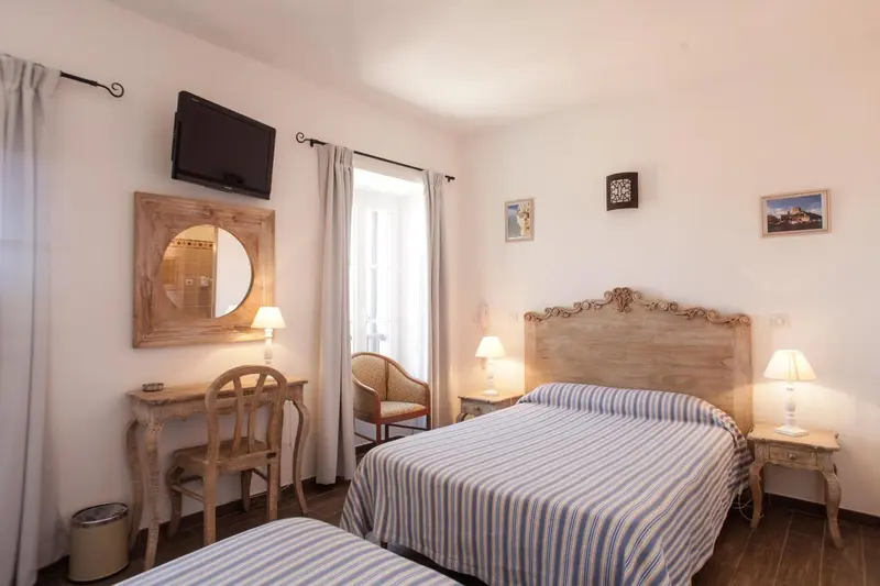 Une chambre lumineuse avec un lit double et un coin coiffeuse.
