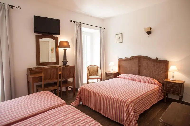 Une chambre lumineuse avec deux lits et un bureau en bois.