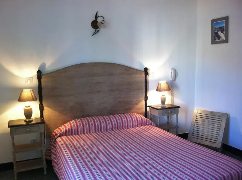 Une chambre lumineuse avec un grand lit recouvert d'une courtepointe rayée.