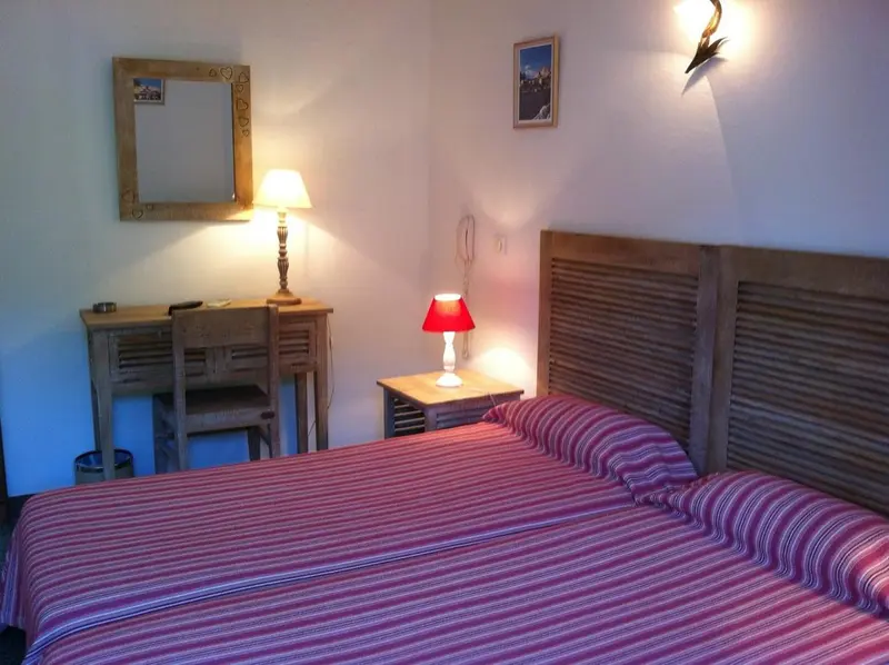 Une chambre lumineuse avec un lit recouvert d'une courtepointe à rayures et un miroir mural.