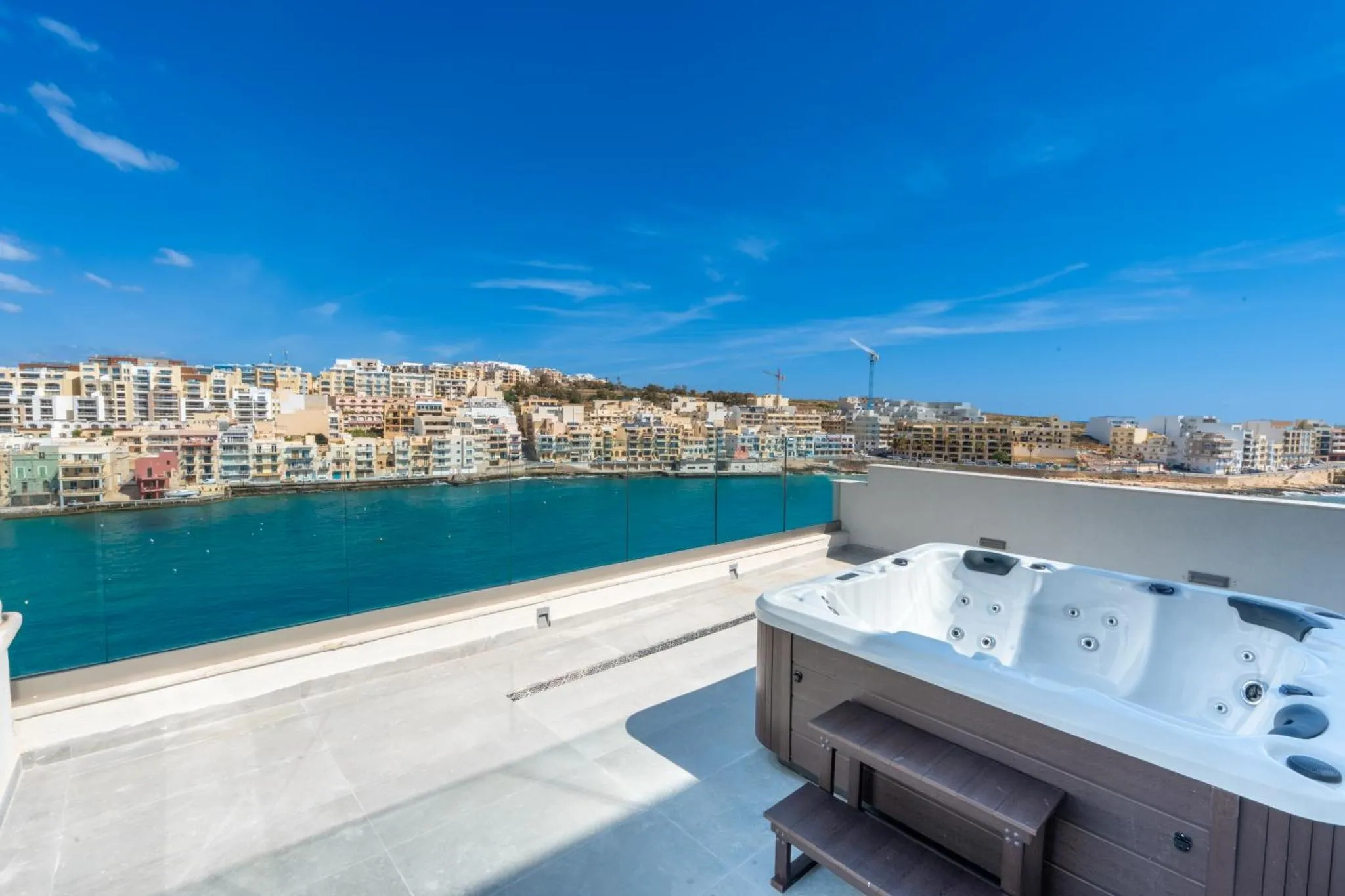 Jacuzzi sur une terrasse avec vue sur la mer et la ville.