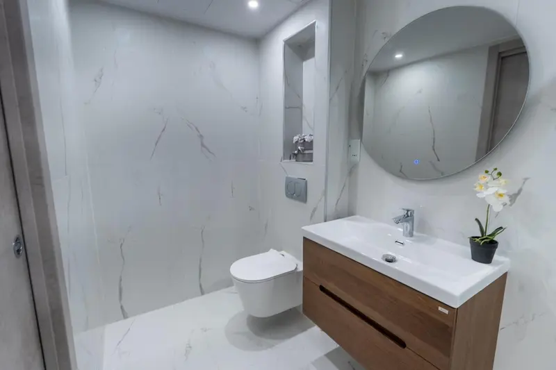 Une salle de bain moderne avec des carreaux blancs et un grand miroir rond.