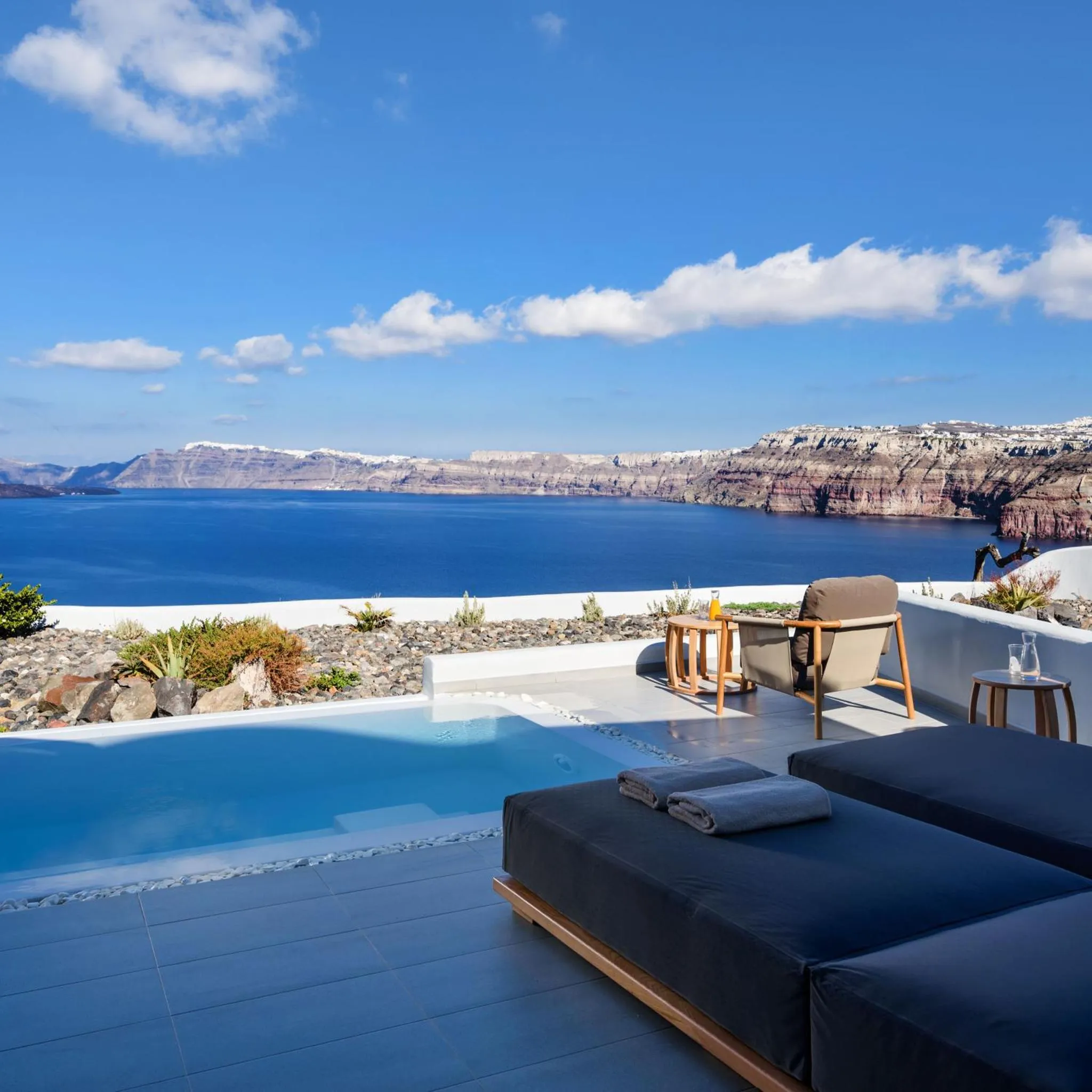Transats et piscine à débordement avec vue sur la mer et les falaises.