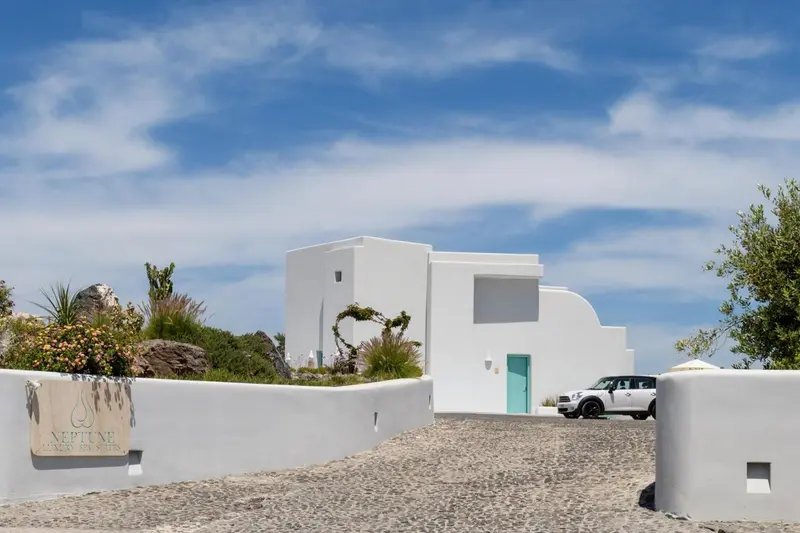 Bâtiment blanc aux lignes épurées avec une porte turquoise et une allée gravillonnée.