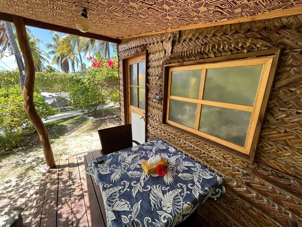 Terrasse ombragée avec mobilier de jardin devant une habitation tropicale.